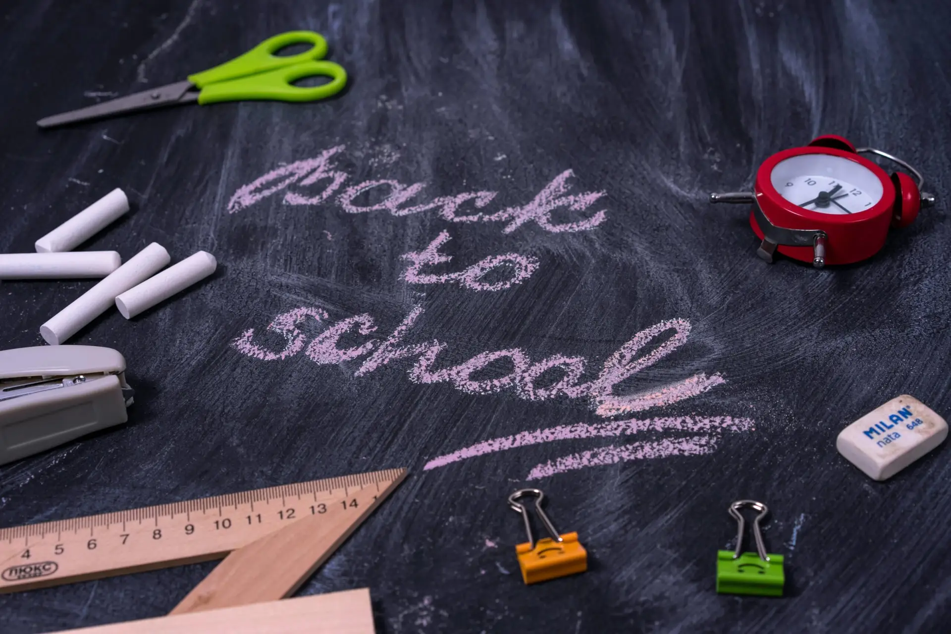 Welcome back to school written on blackboard surrounded by school supplies