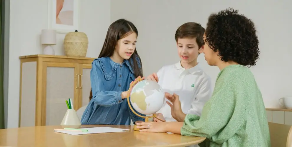 What is a learning pod? In this example, two kids with a teacher looking at a globe together, highlighting the smaller class sizes in a learning pod.