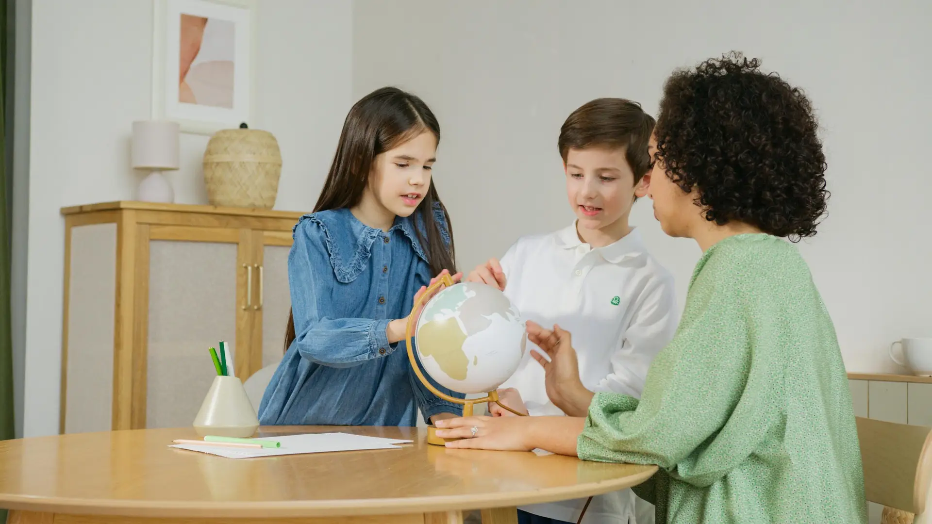 What is a learning pod? In this example, two kids with a teacher looking at a globe together, highlighting the smaller class sizes in a learning pod.