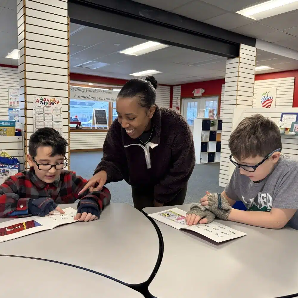 Children learning in small group tutoring with a smiling tutor in Woodbury, CT