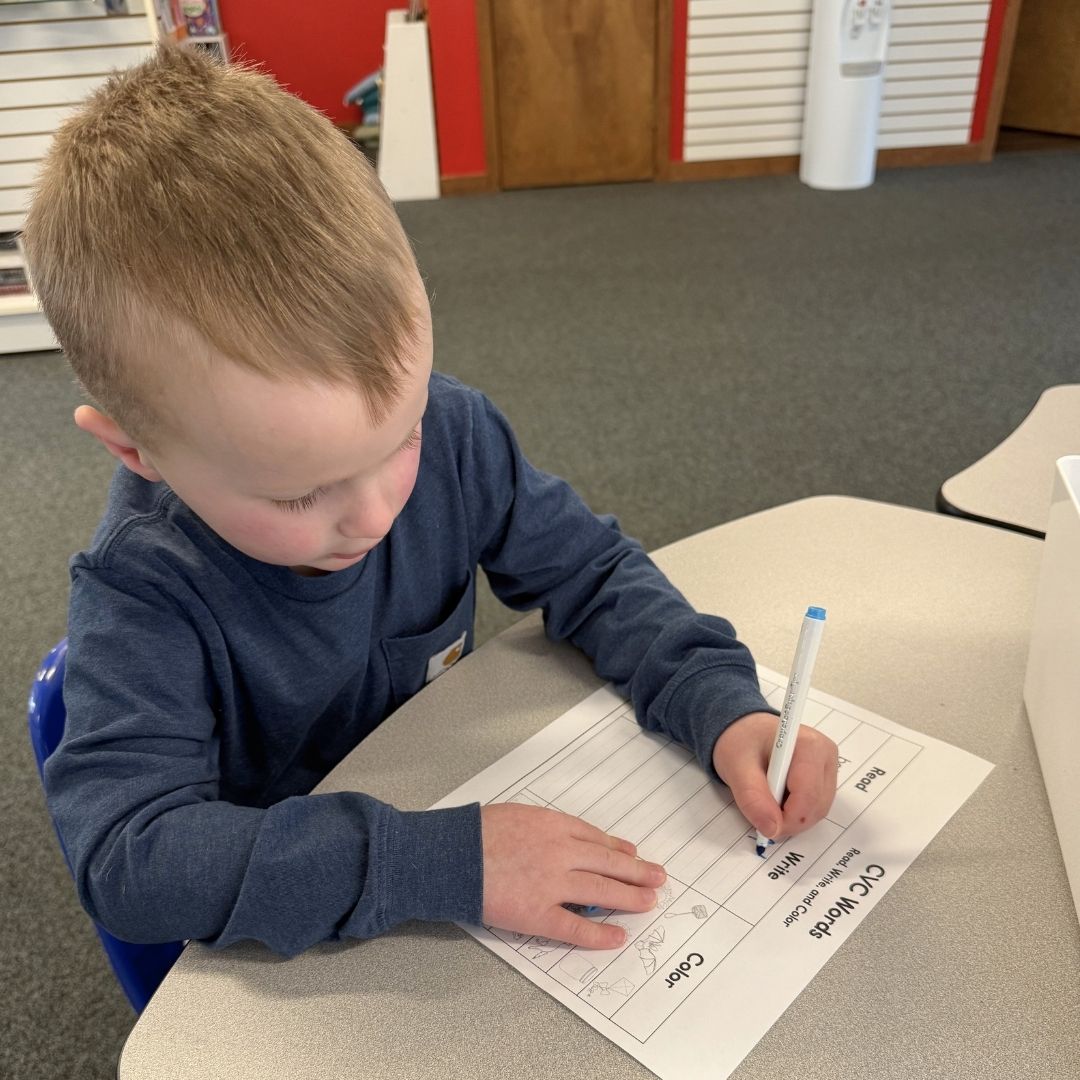 Child writing at private tutoring center table.